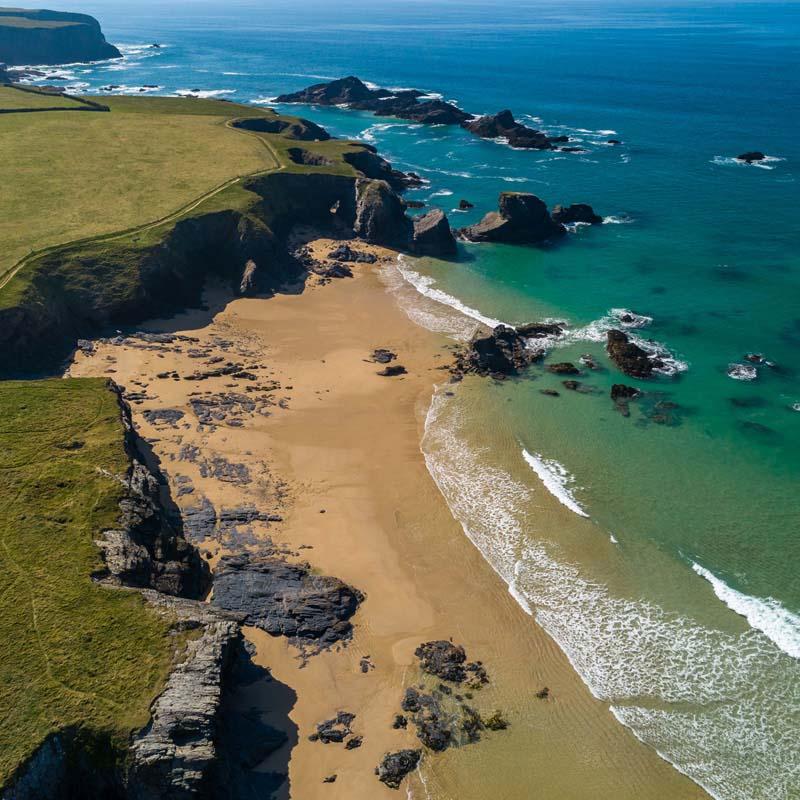Aerial view of a golden Cornish surf beach with turquoise water near Padstow