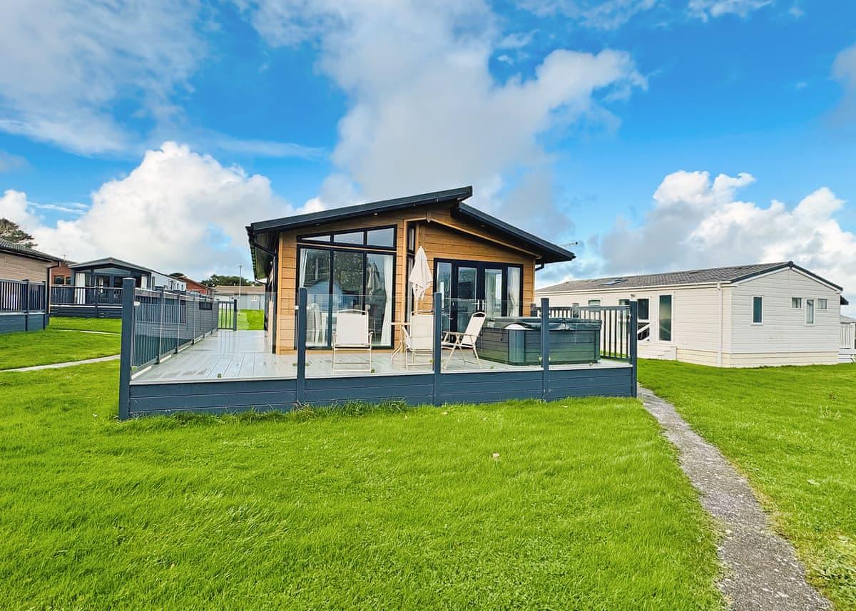 Luxury lodge exterior with raised timber decking and glass balustrade at Atlantic Bays Holiday Park, Padstow