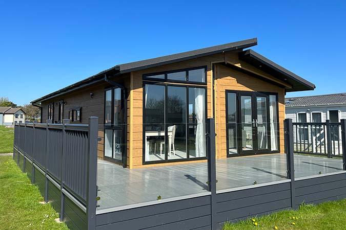 Modern oak-clad lodge for sale with glass-balustrade decking at Atlantic Bays