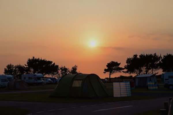 Open grass camping field with countryside beyond at Atlantic Bays Holiday Park, St Merryn
